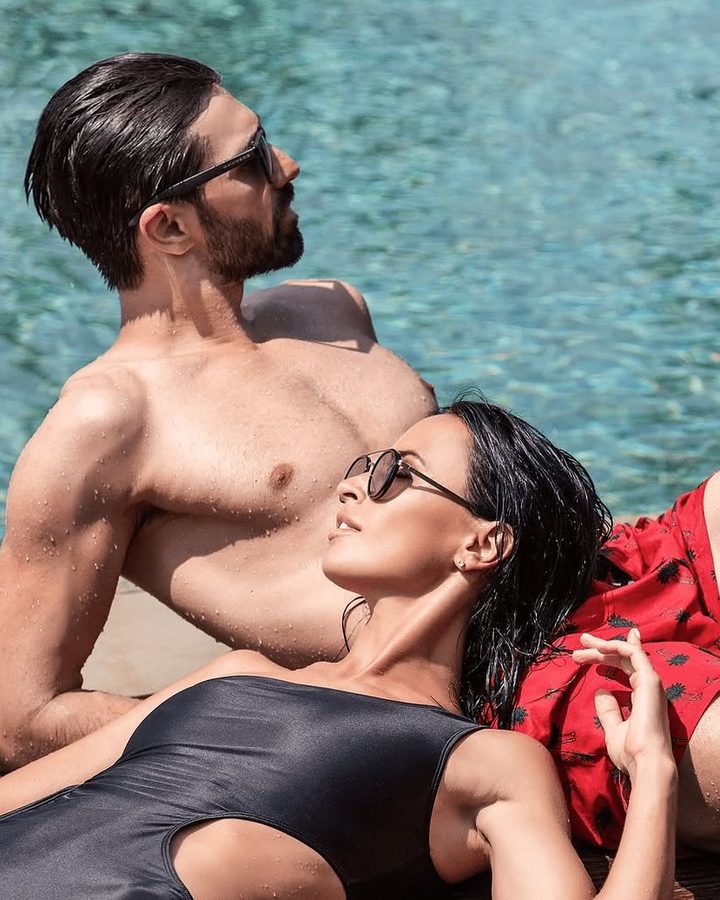 Two models in swimwear and sunglasses beside a pool